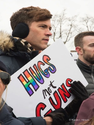 Young man holding sign Hugs not Guns